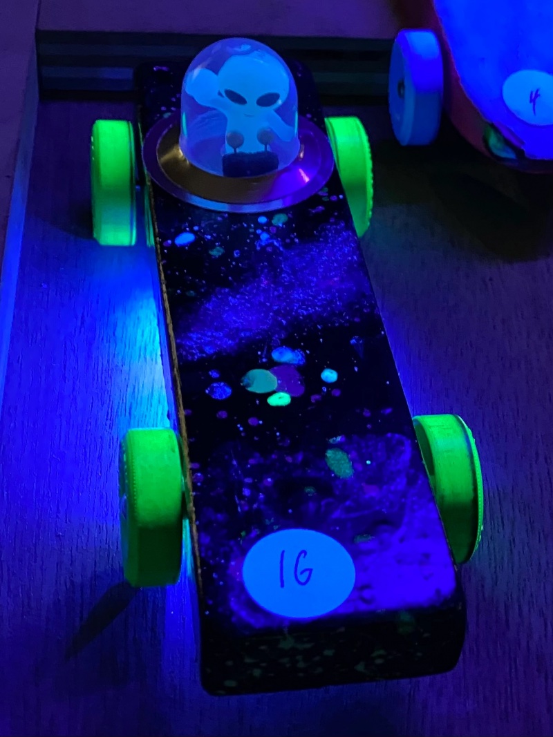 Alien-themed Pinewood Derby car glowing under black light