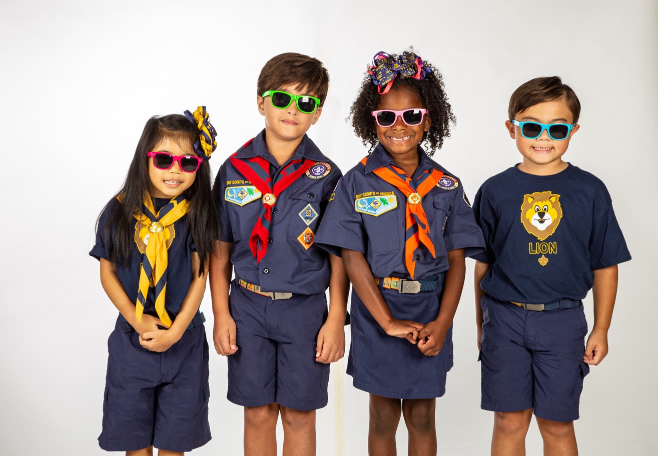 Four Cub Scouts wearing uniforms and colorful sunglasses